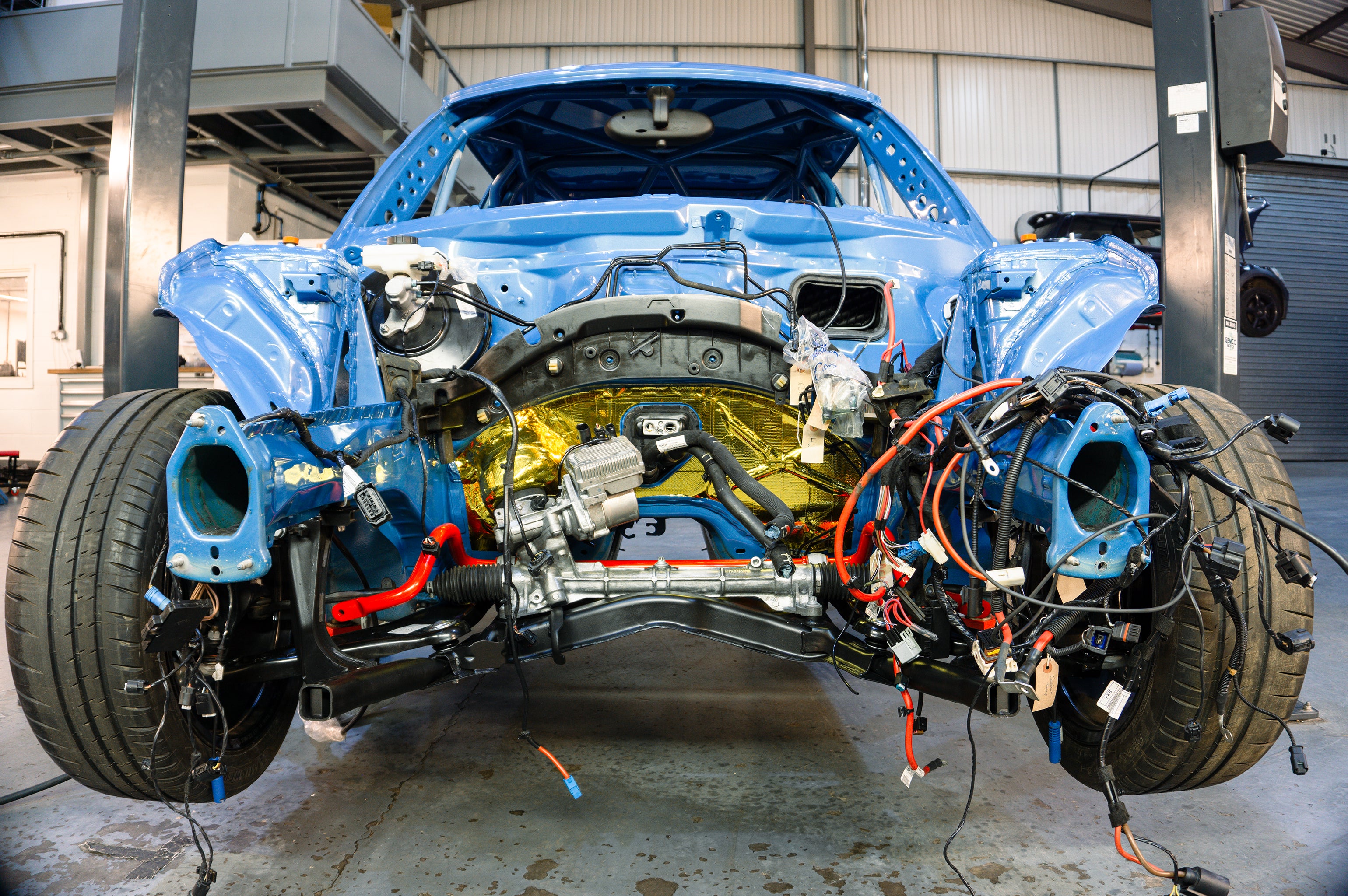 Lohen vehicle technician preparing a MINI R56 for rust treatment underneath.