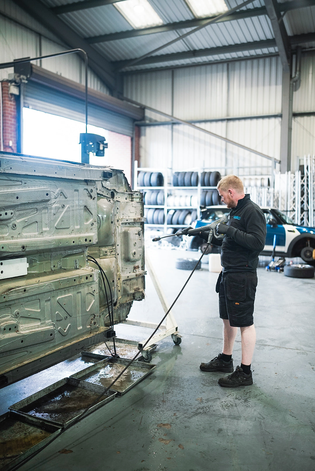 Lohen vehicle technician preparing a MINI R56 for rust treatment underneath.